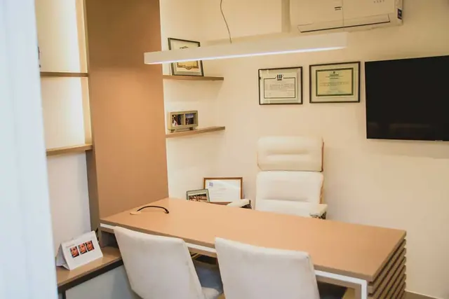 Sala de atendimento com mesa e certificados na parede